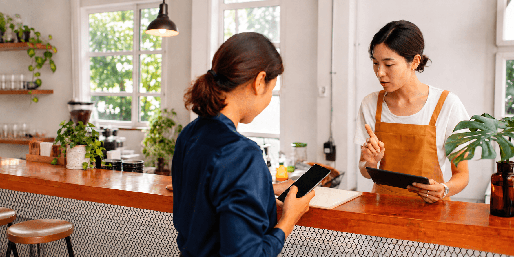 Two restaurant team members reviewing tablets at a café counter